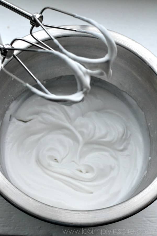 closeup overhead of whipped coconut milk in a silver mixing bowl