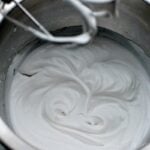 whipped coconut milk in a silver mixing bowl