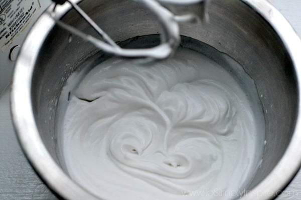 whipped coconut milk in a silver mixing bowl with beaters