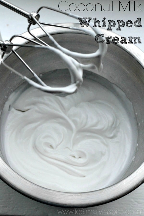 whipped coconut milk in a silver mixing bowl with beaters