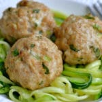 three asian meatballs on top of zucchini noodles in a white bowl