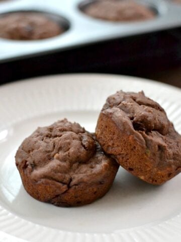 A close up of a piece of two chocolate muffins on a plate,