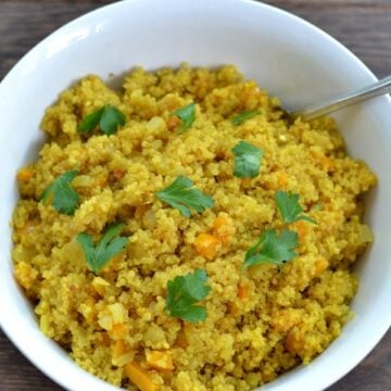 a white bowl of Curried Quinoa with a serving spoon