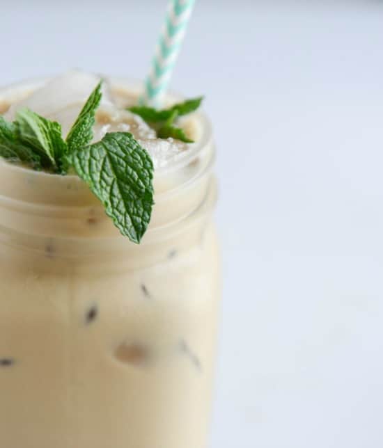 a closeup of iced coffee in a glass with mint sprigs 