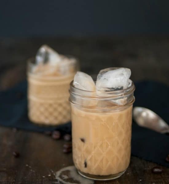 two mason jars with iced coffee with cubes of ice on top