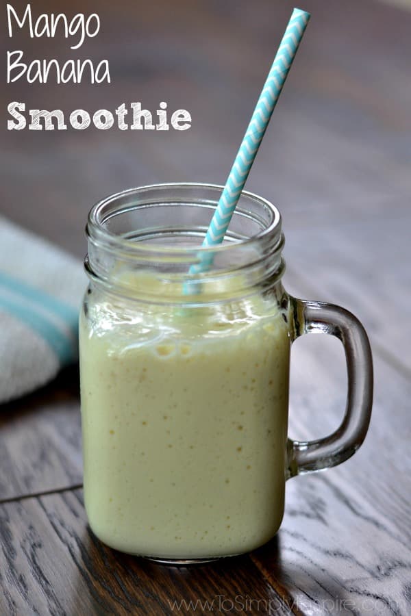 A glass mug with mango banana smoothie on a wood table 