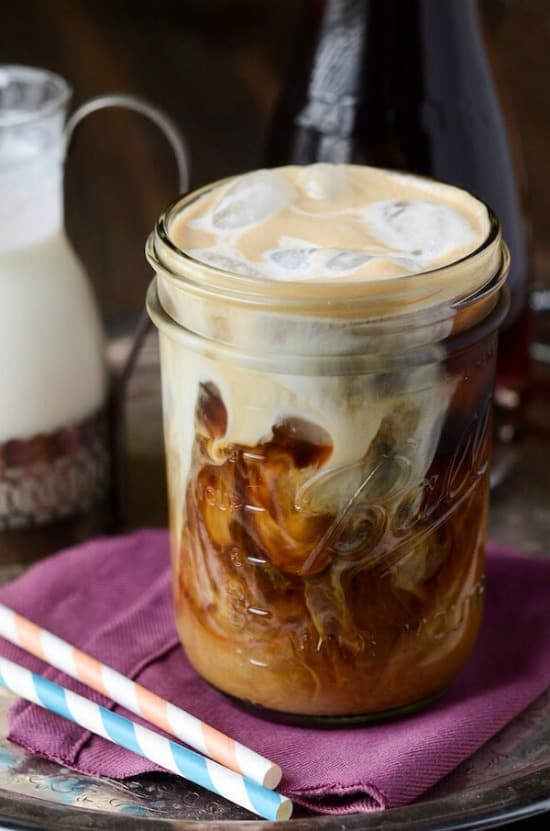 a mason jar with icd coffee with cream on top