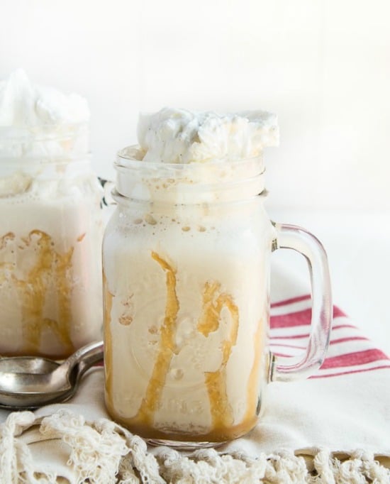 two glass mugs of iced coffee with whipped cream 