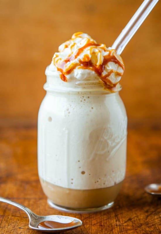 a mason jar with caramel frappuccino with whipped cream and caramel sauce.