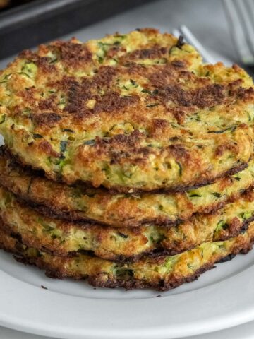 stack of four zucchini fritters on a white plate