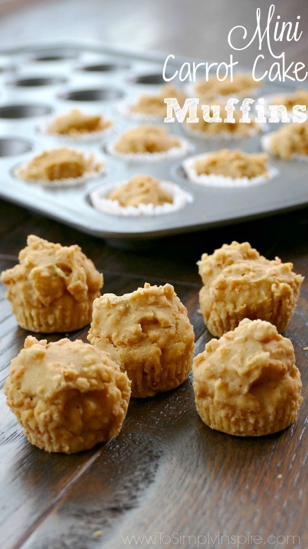 five mini carrot cake muffins on a wood table with a muffin tin in the background