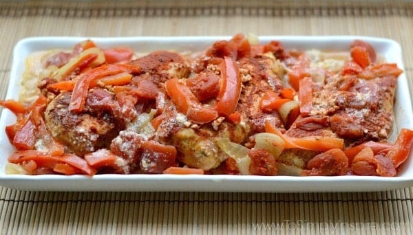 A closeup of a white plate white Chicken with sliced red bell peppers and paprika