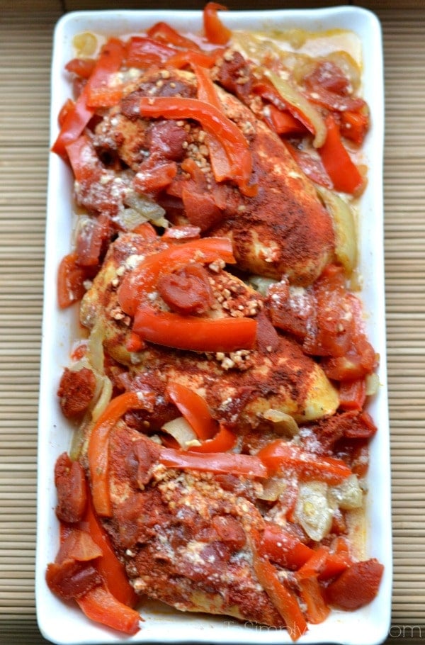 A rectangle white plate of Chicken with sliced red bell peppers and paprika