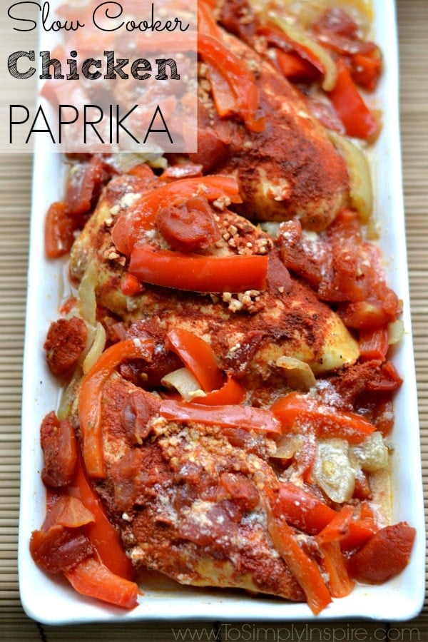 A white plate of Chicken with sliced red bell peppers and paprika