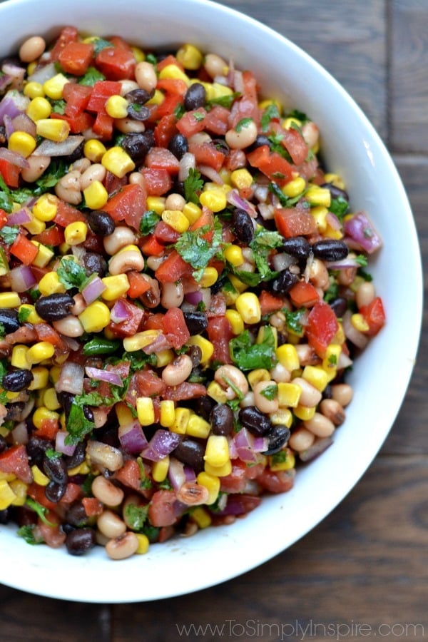 closeup of Cowboy Caviar recipe with corn black beans, tomatoes and cilantro in a white bowl