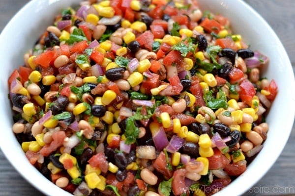 closeup of Cowboy Caviar recipe with corn black beans, tomatoes and cilantro in a white bowl