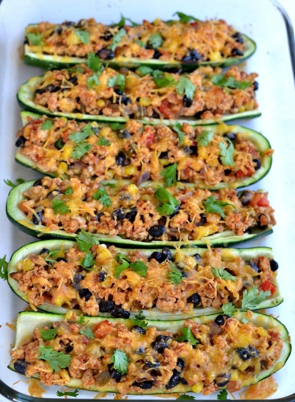 Vertical closeup of Mexican Zucchini Boats recipe with chicken, black beans and cheese and cilantro in a casserole dish