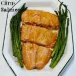 a white plate with 3 salmon slices and asparagus on the side