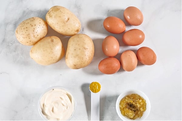 4 whole potatoes 7 hard-boiled eggs, mayo, relish and a teaspoon of mustard on a counter