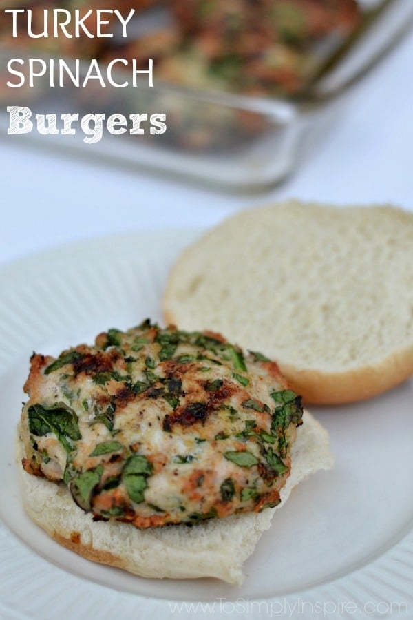 Spinach turkey burger on a open bun on a white plate