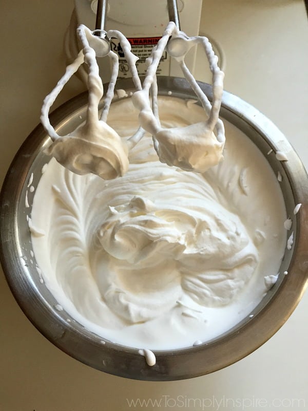 Bowl of whipped cream with beaters over top