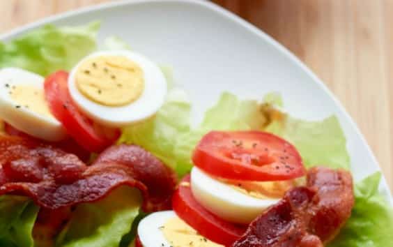 two BLT lettuce Wraps topped with tomato slices, bacon and hard boiled egg slices