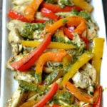 chicken with strips of red, orange and yellow bell pepper strips topped with a cilantro lime sauce