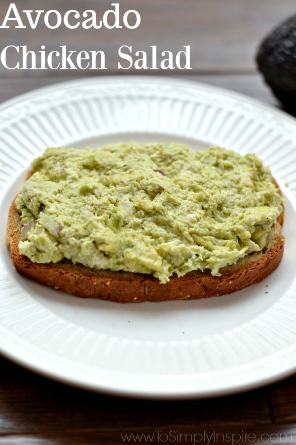 A white plate with a piece of bread on a plate with Avocado Chicken salad on top