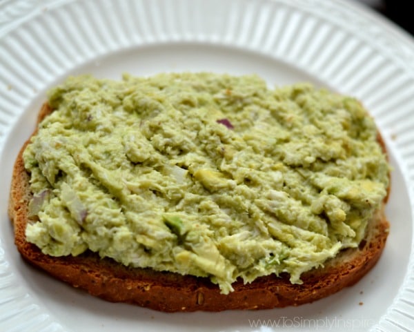 Closeup of Avocado Chicken Salad on a slice of bread on a white plate.