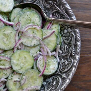 Creamy Cucumber Salad recipe in a big silver bowl with a serving spoon