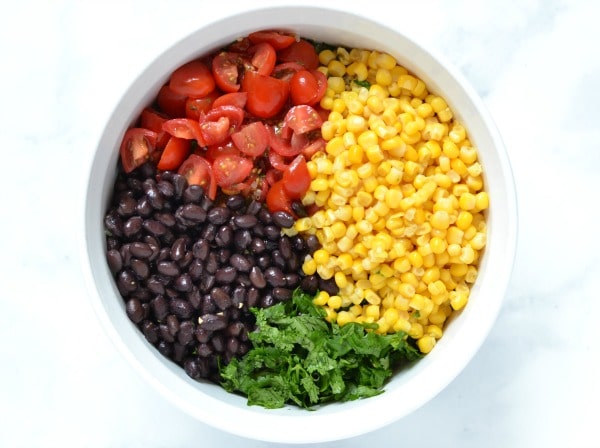 black beans, corn, cilantro, and tomatoes in a white bowl