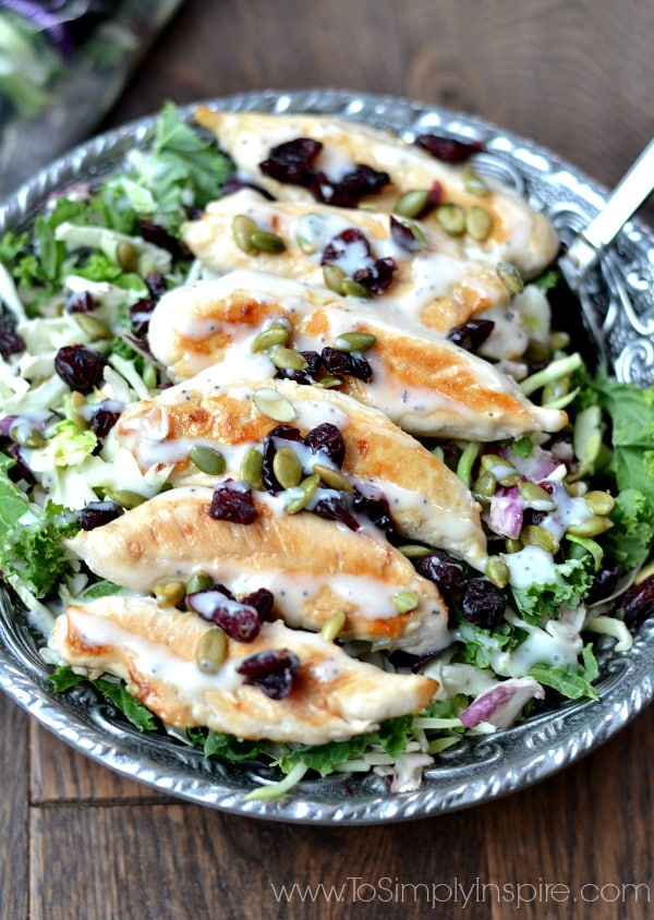 Chicken tenders on top of Kale Salad in a big silver bowl.