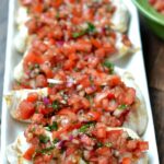 closeup of 5 chicken breasts topped with bruschetta tomato sauce