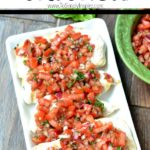 chicken breasts topped with bruschetta tomatoes on a rectangle white plate