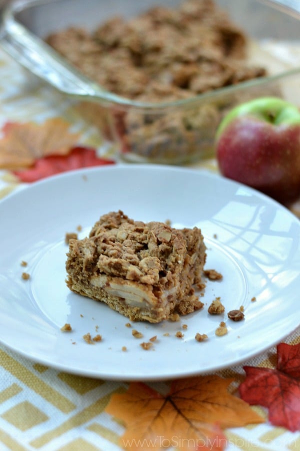 Apple Oatmeal Crumb Bar on a white plate with an apple and dish in the background.