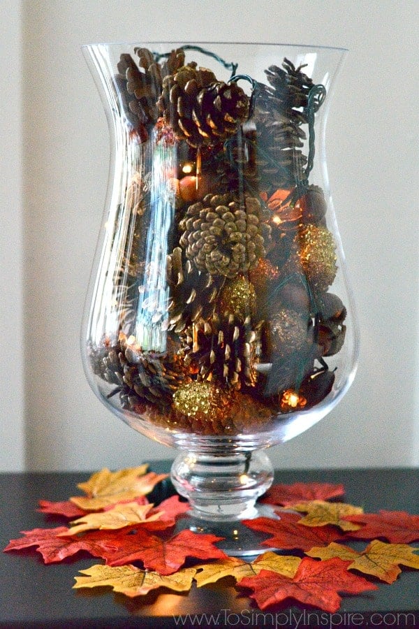 Pine cones in a tall glass vase with fairy lights