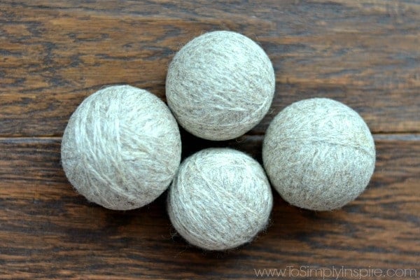 4 gray DIY wool dryer balls on a wood floor
