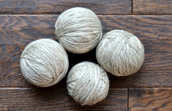 four gray wool dryer balls on a wood floor