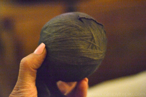 wool yarn ball in a black stocking held in fingers