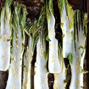 roasted boy choy stalks with minced garlic on a baking sheet.