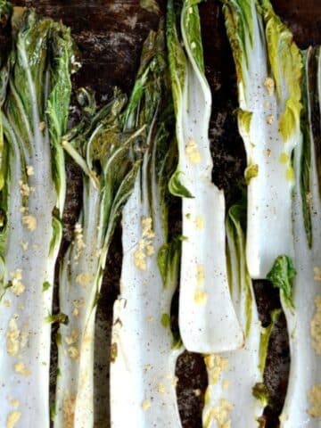 roasted boy choy stalks with minced garlic on a baking sheet.