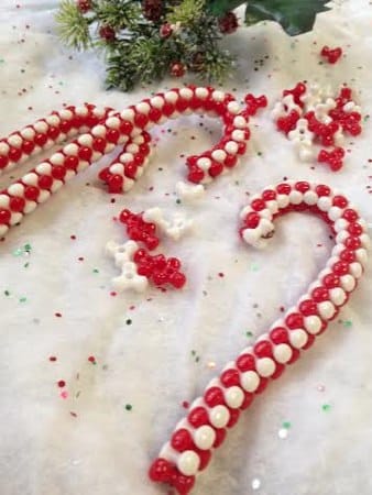 a closeup of a beaded candy cane Christmas ornament laying on a white background