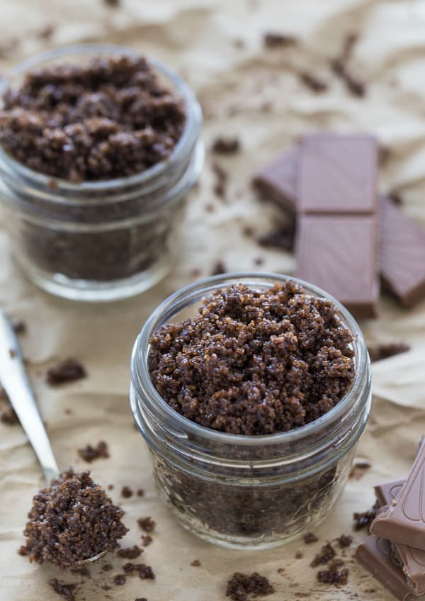 chocolate sugar scrub in a small mason jar with a spoon of cocoa and chocolate bars pieces 