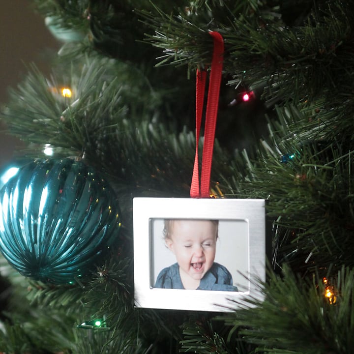 a closeup of a photo Christmas ornament hanging on a tree