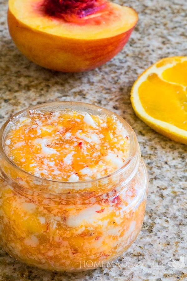 orange sugar scrub in a glass jar with orange slice beside