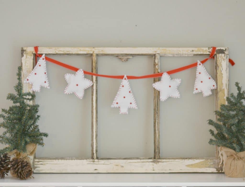 five white felt christias trees hanging on a red string