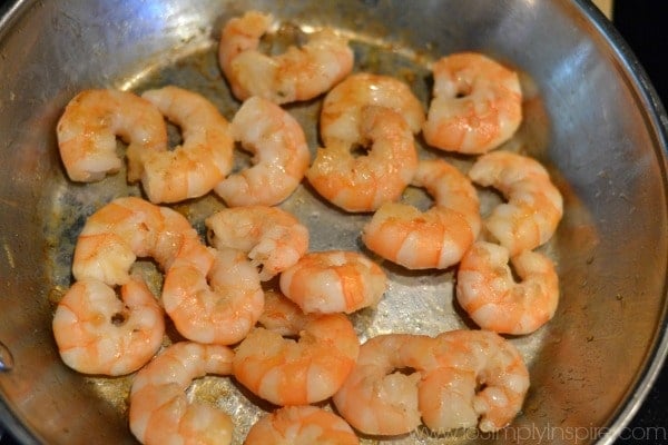 unpeeled shrimp cooking in a stainless steel pan