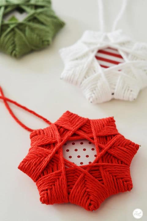 a closeup of a red and a white DIY Yarn Christmas star ornament  