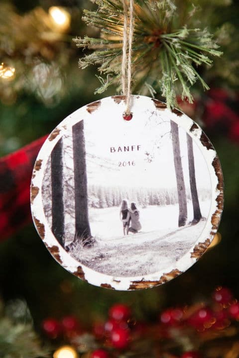 a closeup of a photo Christmas ornament made of wood hanging on a tree