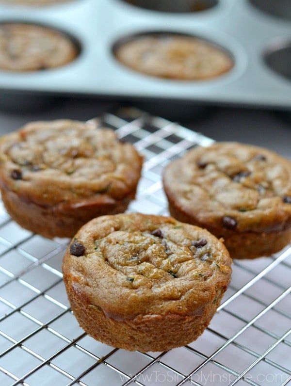 3 gluten free zucchini muffins on a cooling rack with muffin tin in the background